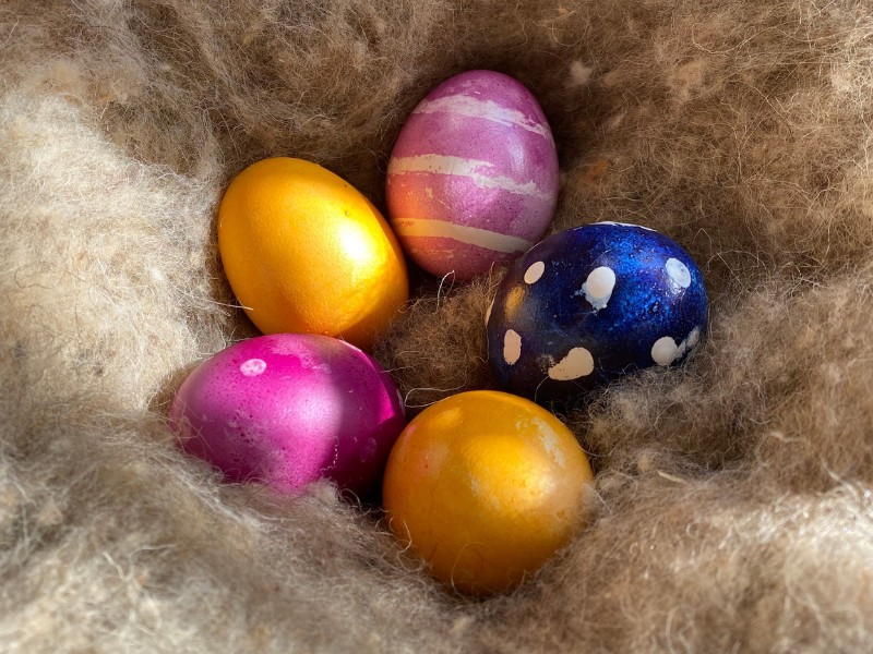 Natürliches Osternest aus Schafwolle mit bunten Naturfarben-Eiern mit Punkten und Streifen